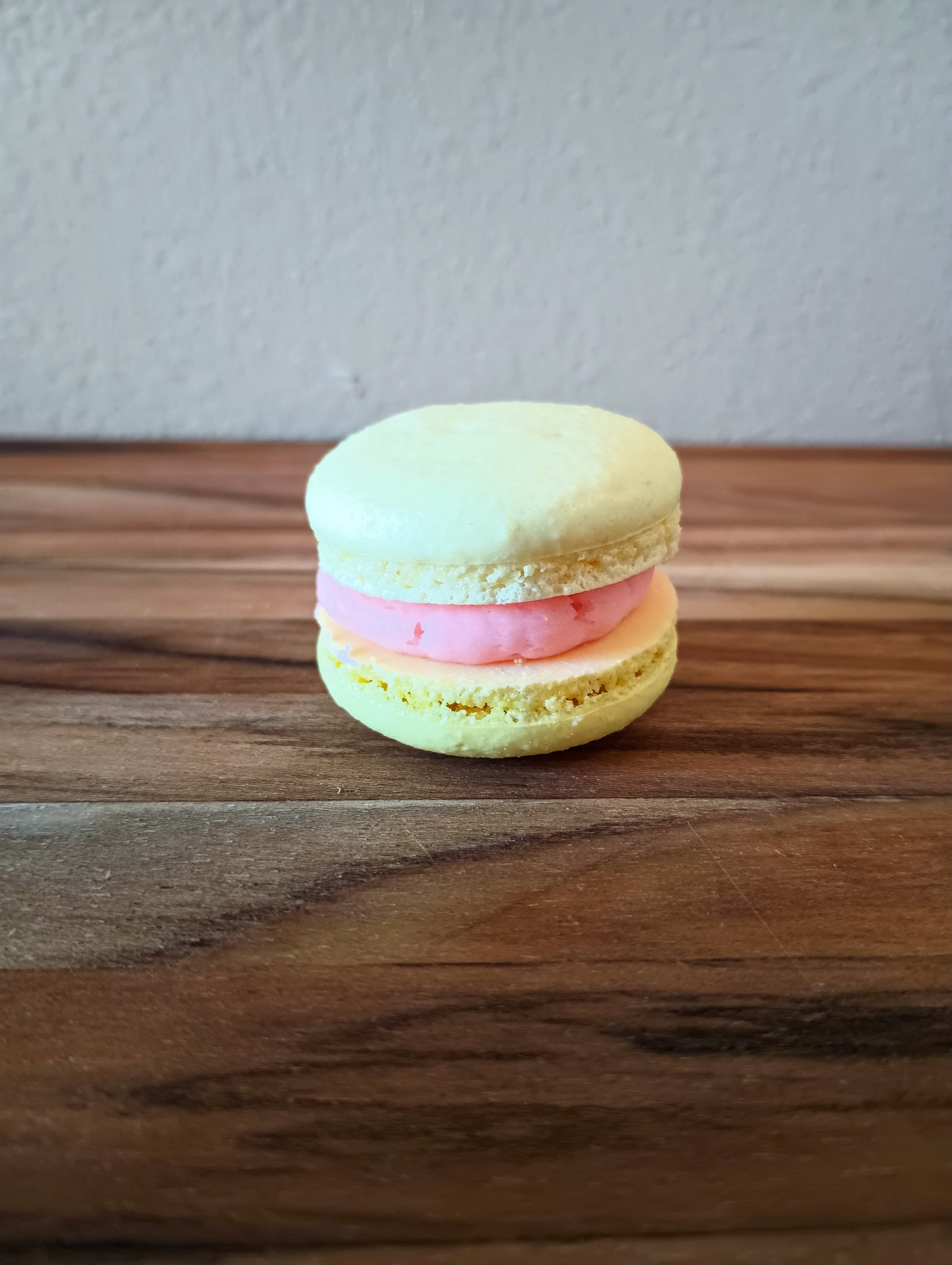 A yellow lemon and raspberry macaron
