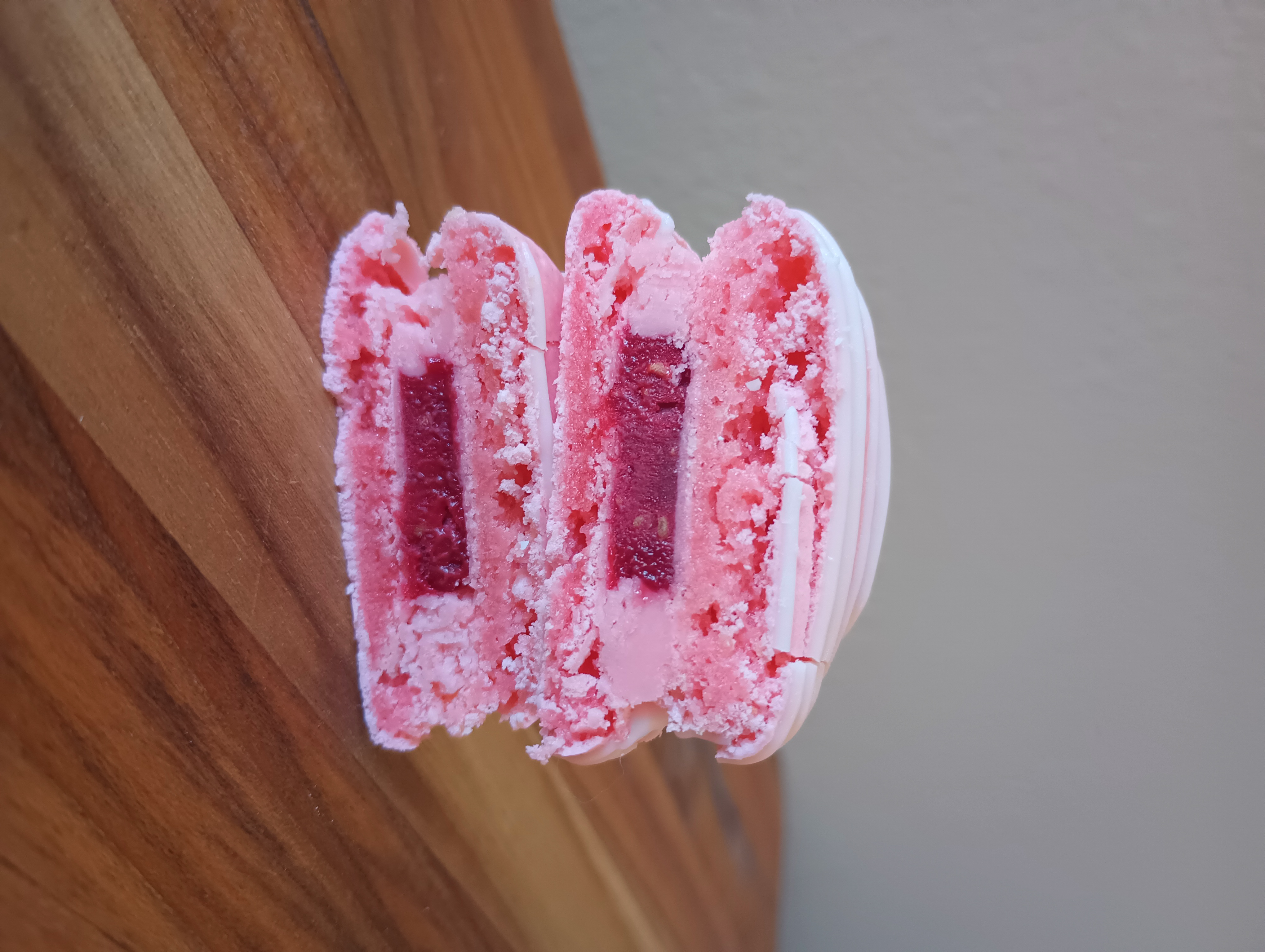 A pink raspberry macaron cut in half to show the filling