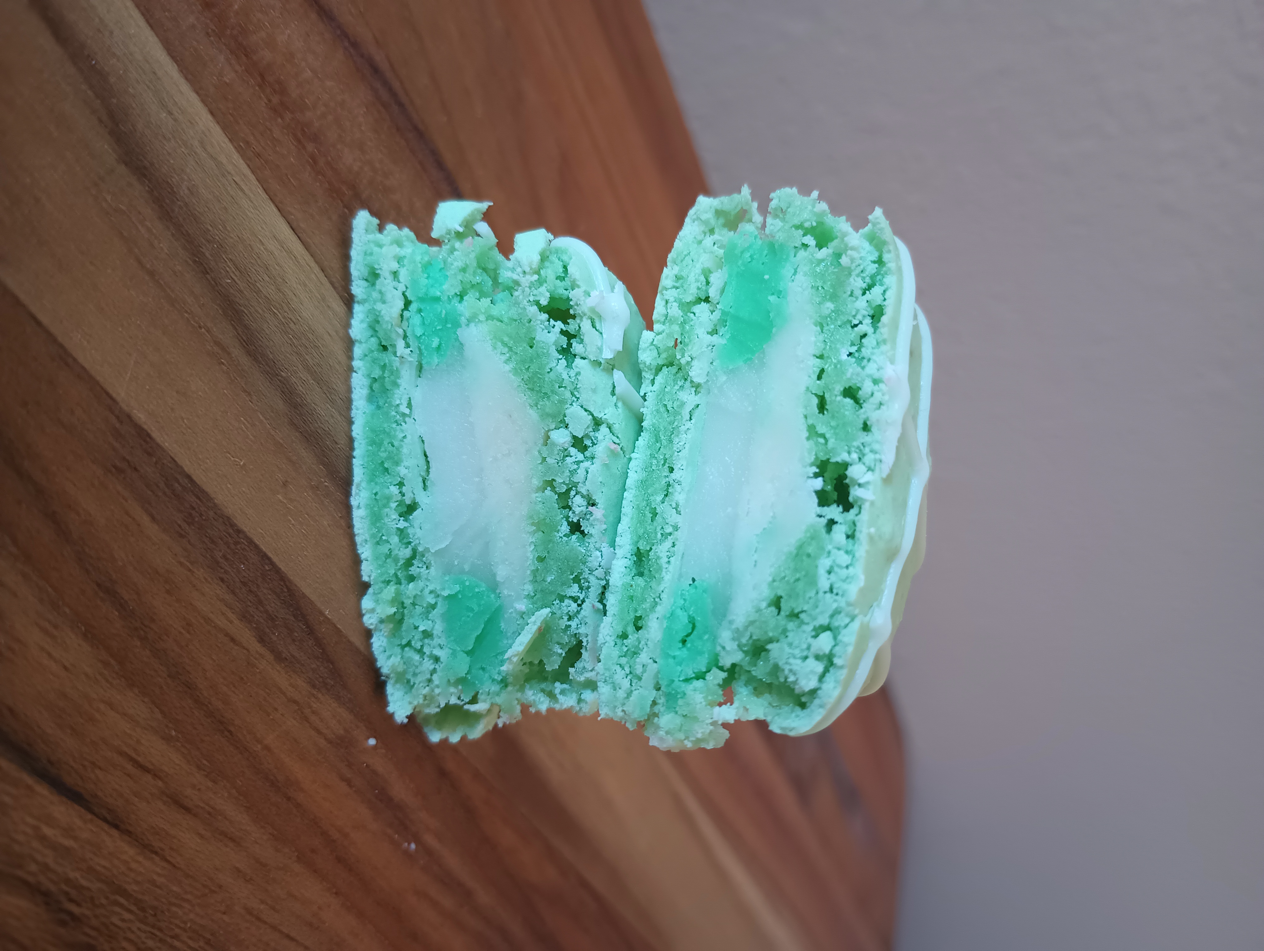 A green key lime pie macaron cut in half to show the filling