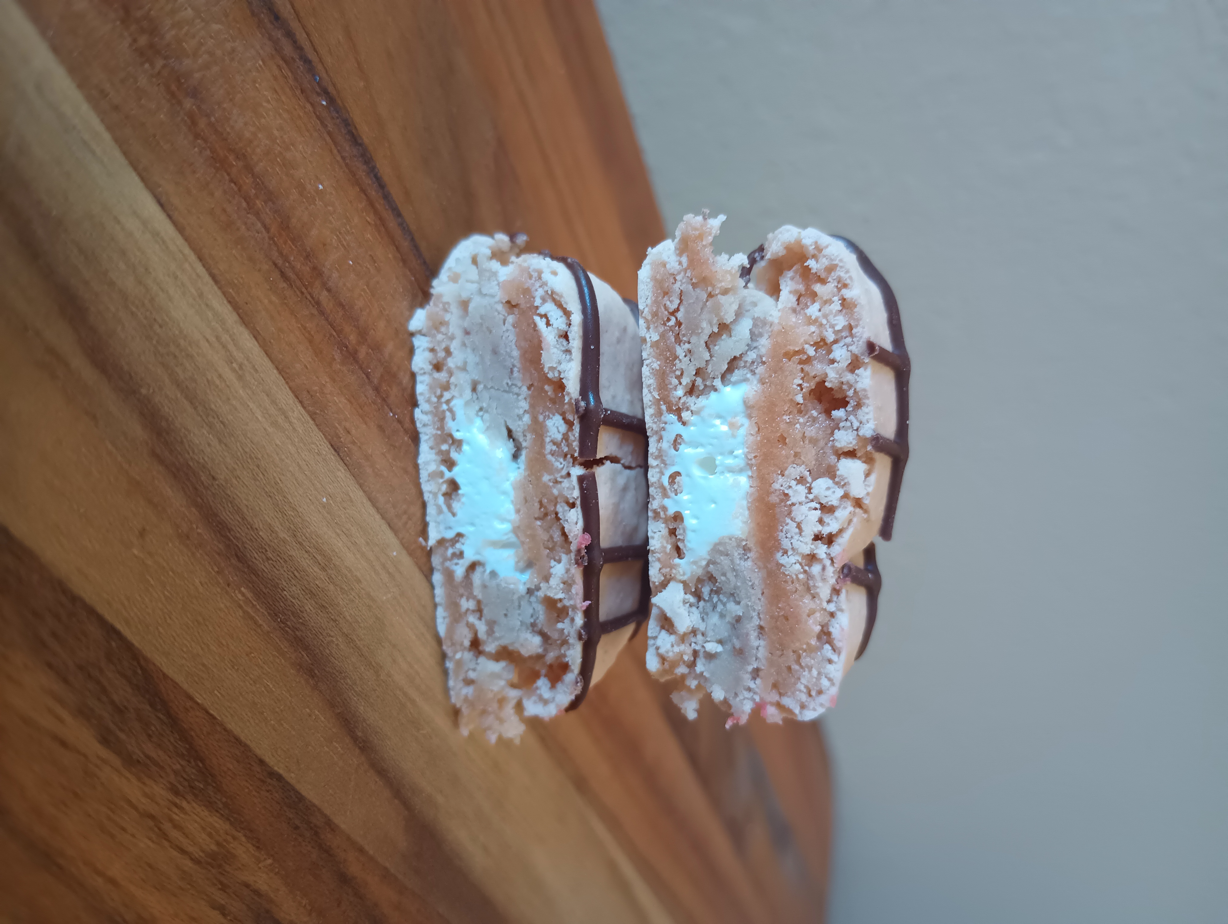 A brown campfire s'mores macaron with a white cream filling cut in half to show the fillings